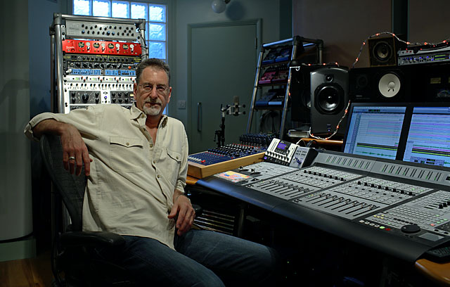 mick glossop sitting behind the mixing console at his private music recording studio in london, uk